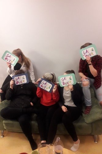 Viisi nuorta sohvalla. Nuorilla on laput kasvojen edessä. Lapuissa teksti: Game over.