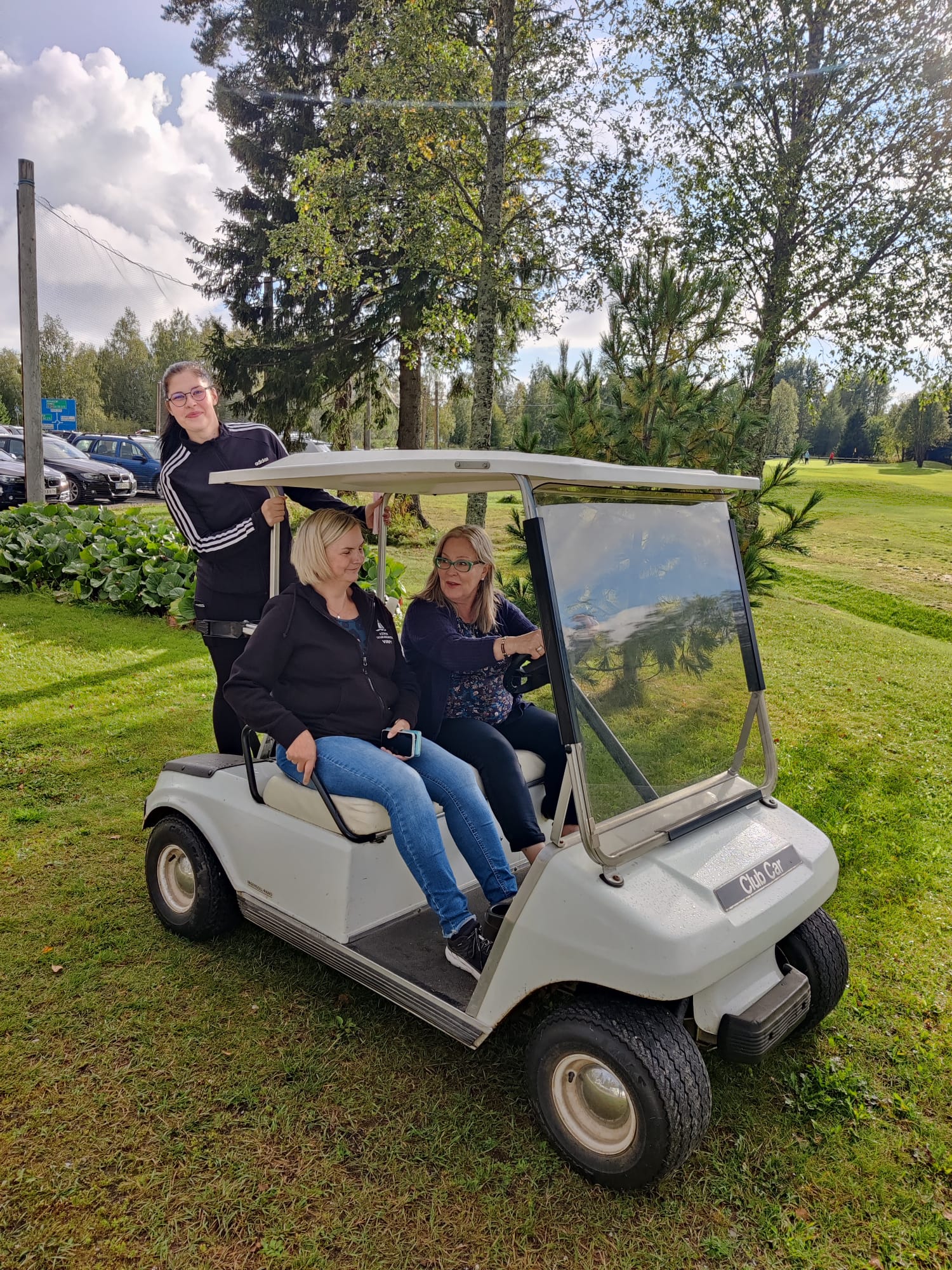 Kolme naista golfkentällä autossa