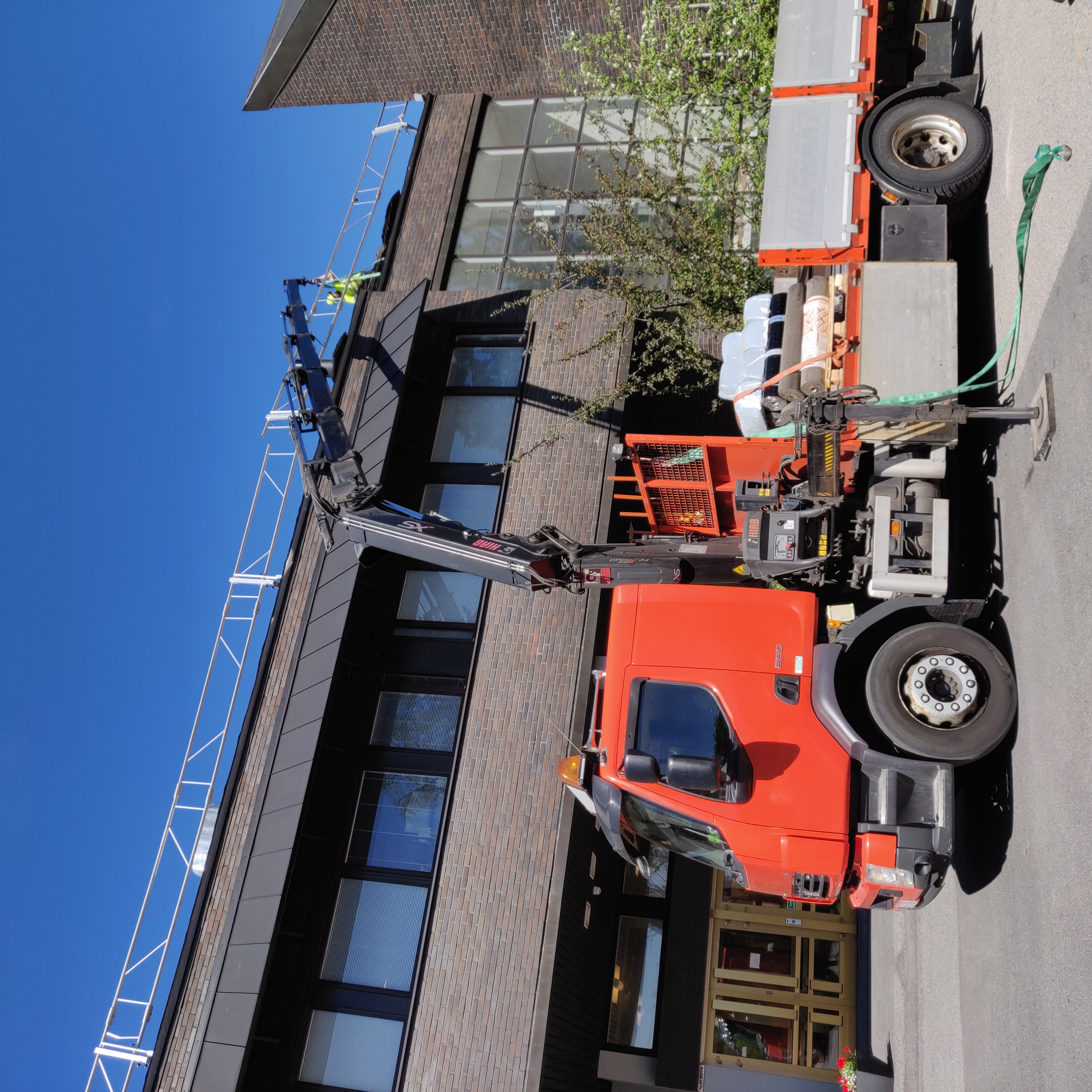 Tummatiilinen seurakuntakeskus, jonka edessä kuorma-auto. Seurakuntakeskuksen katolla rakennustelineitä.